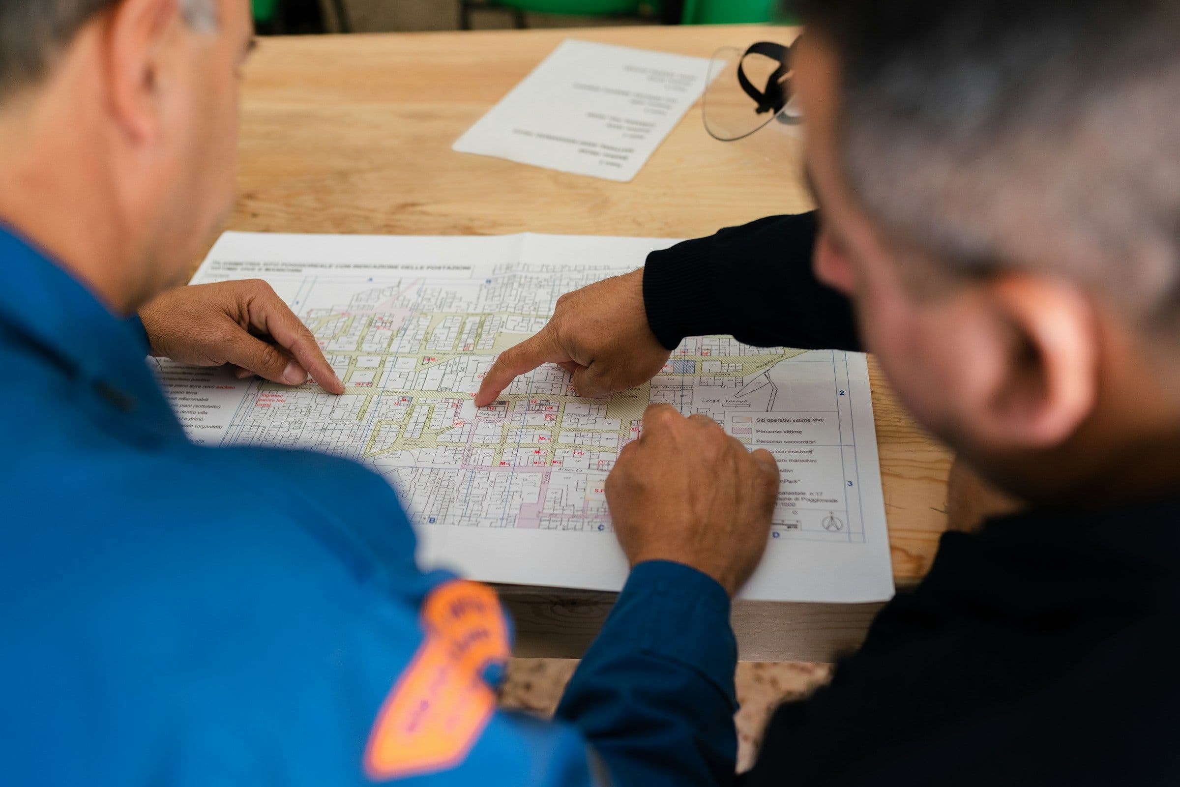 Two engineers reviewing a printed plan spread on a table