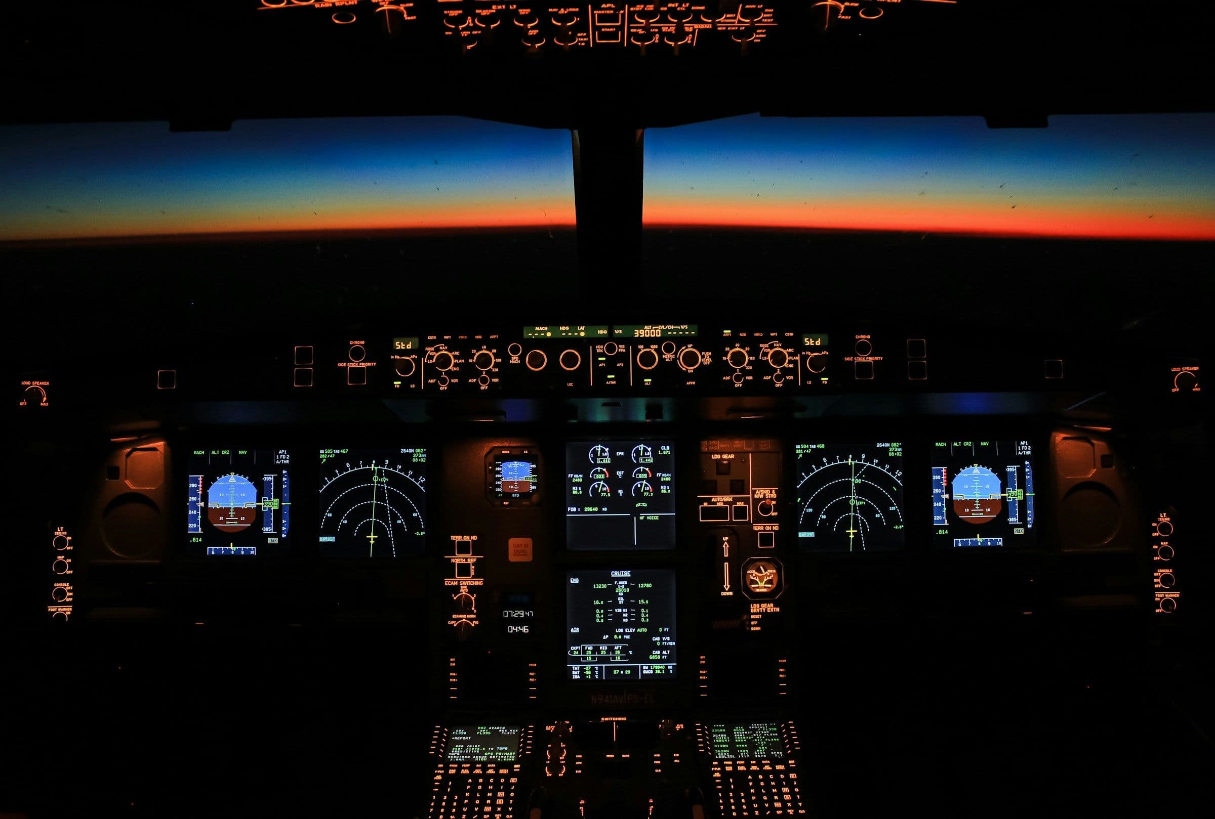An airplane cockpit at night with glowing instrument panels and a horizon line